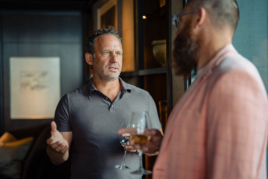 Jonathan Raymond mid-conversation with a guest, drinks in hand