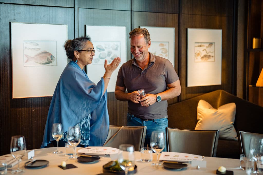 Jonathan Raymond laughing with a guest beside the set dinner table